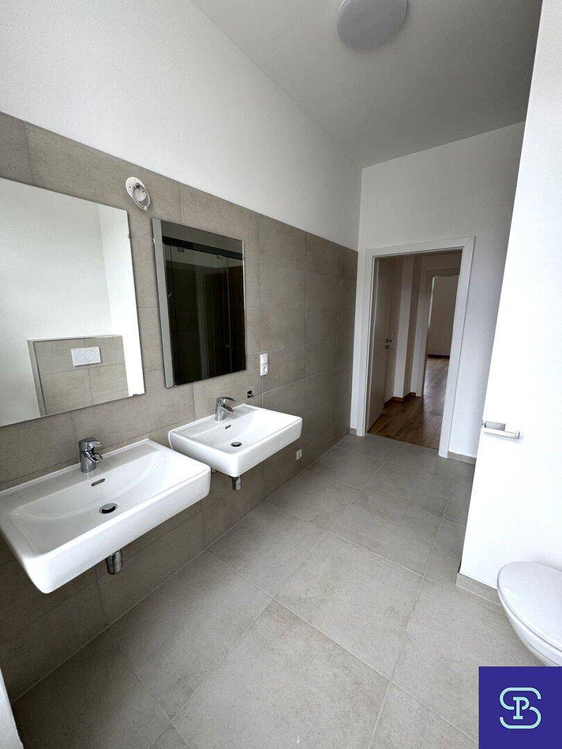 Modernes Badezimmer mit Doppelwaschbecken, Spiegeln und Fliesen an den Wänden.