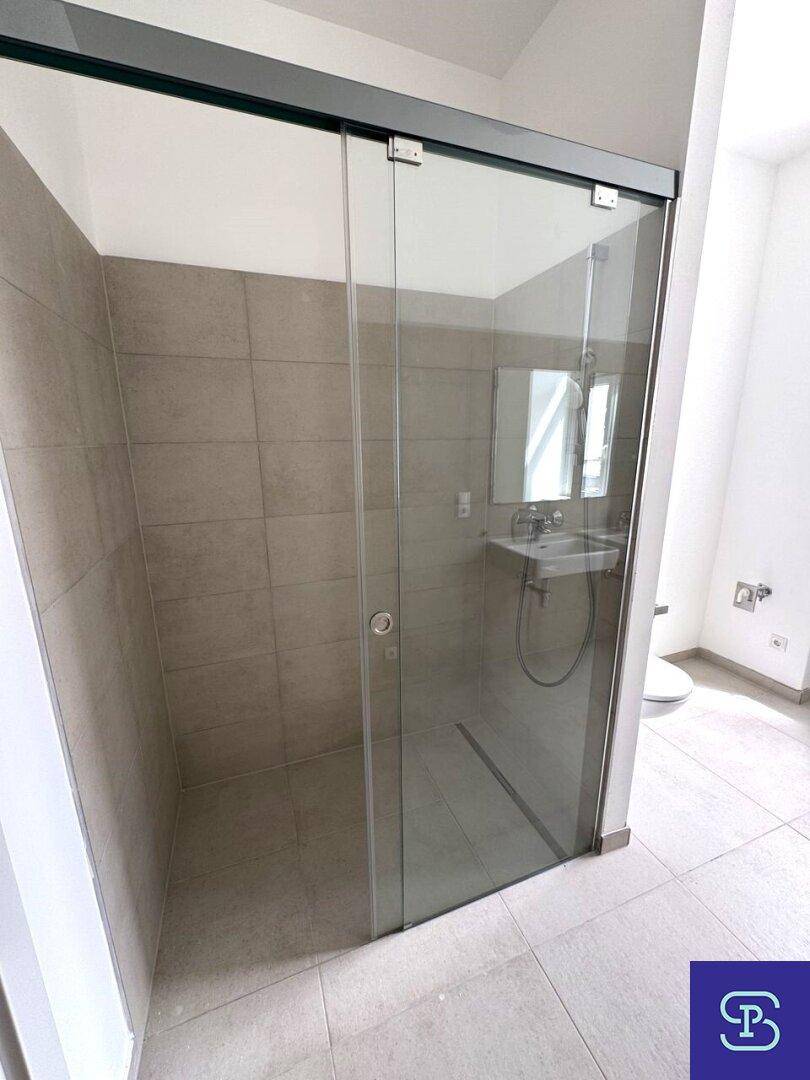 Geräumige, begehbare Dusche mit Glasabtrennung und modernen Fliesen im Badezimmer.