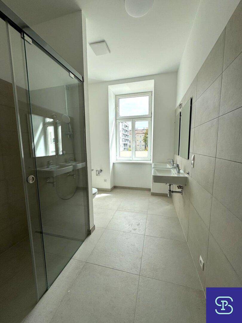 Modernes Badezimmer mit begehbarer Dusche, Doppelwaschbecken und großem Fenster.