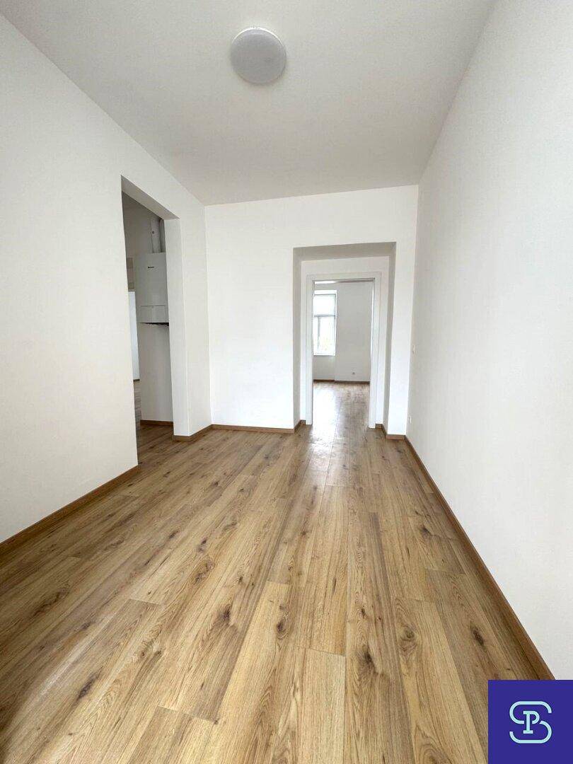 Langer Flur mit Laminatboden und weiß gestrichenen Wänden, der verschiedene Räume verbindet.