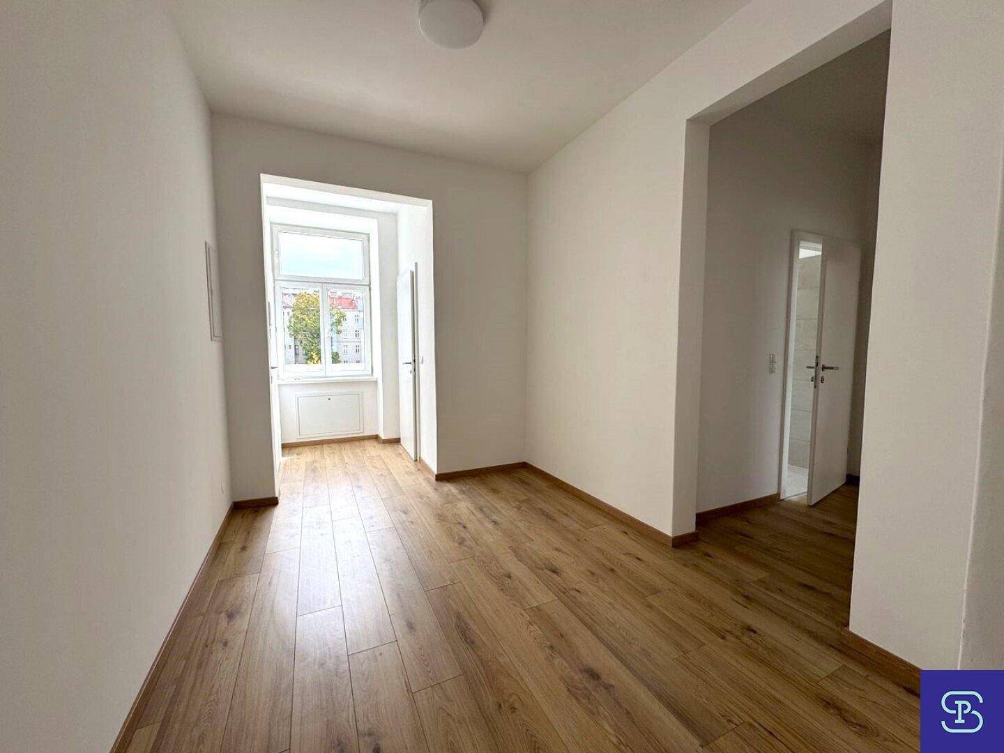 Heller Flur mit Laminatboden und einem Fenster, das den Eingangsbereich mit Licht erfüllt.