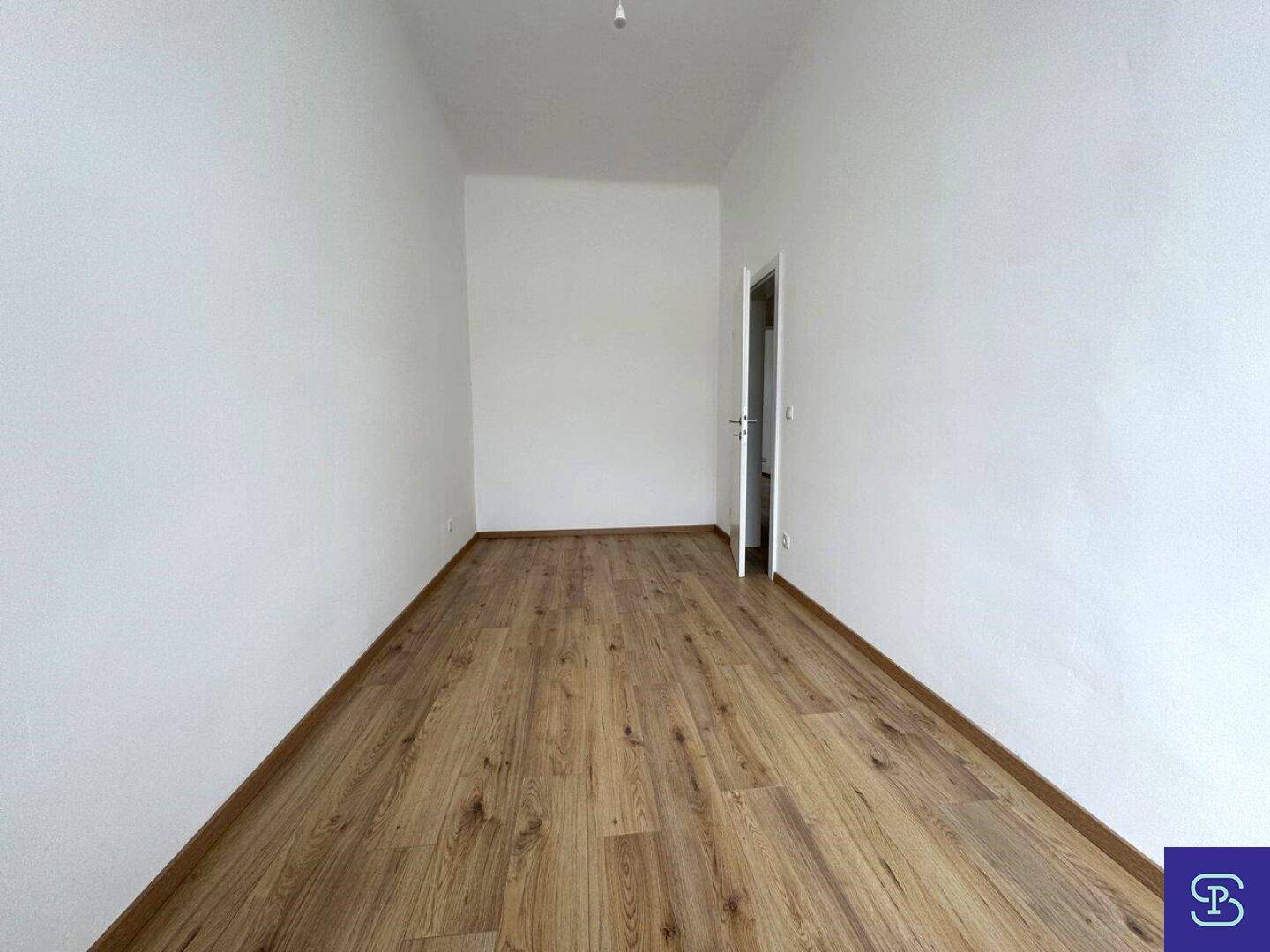Leerer, länglicher Raum mit Laminatboden und weiß gestrichenen Wänden, ideal als Schlaf- oder Arbeitszimmer.