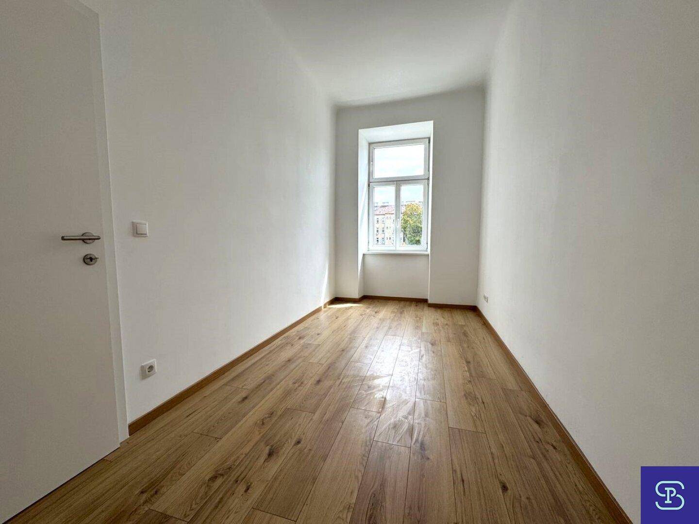 Schmaler Raum mit Laminatboden und einem Fenster, das für natürliche Belichtung sorgt.