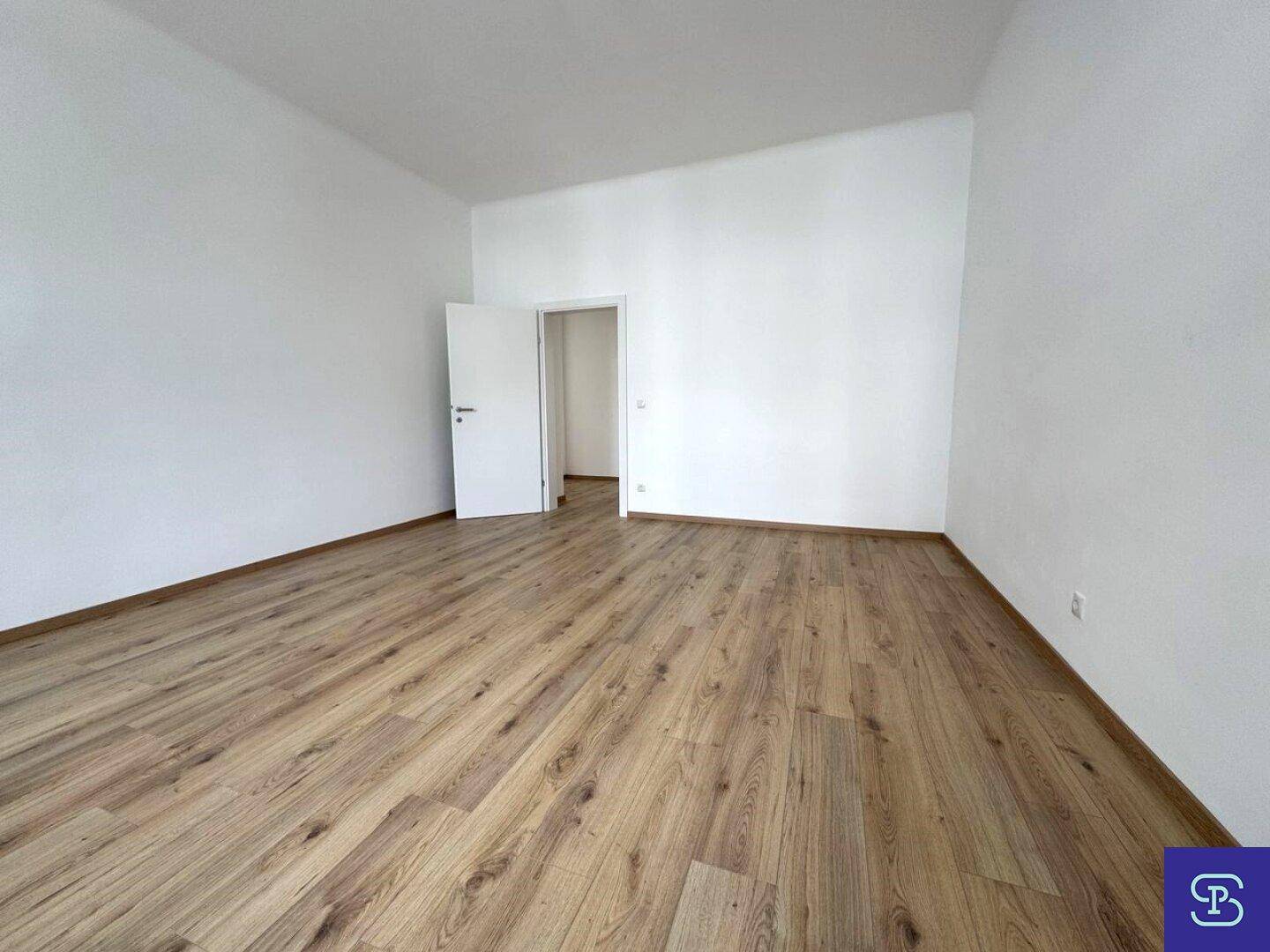 Leeres Zimmer mit Laminatboden und weiß gestrichenen Wänden, bietet viel Platz für individuelle Einrichtung.
