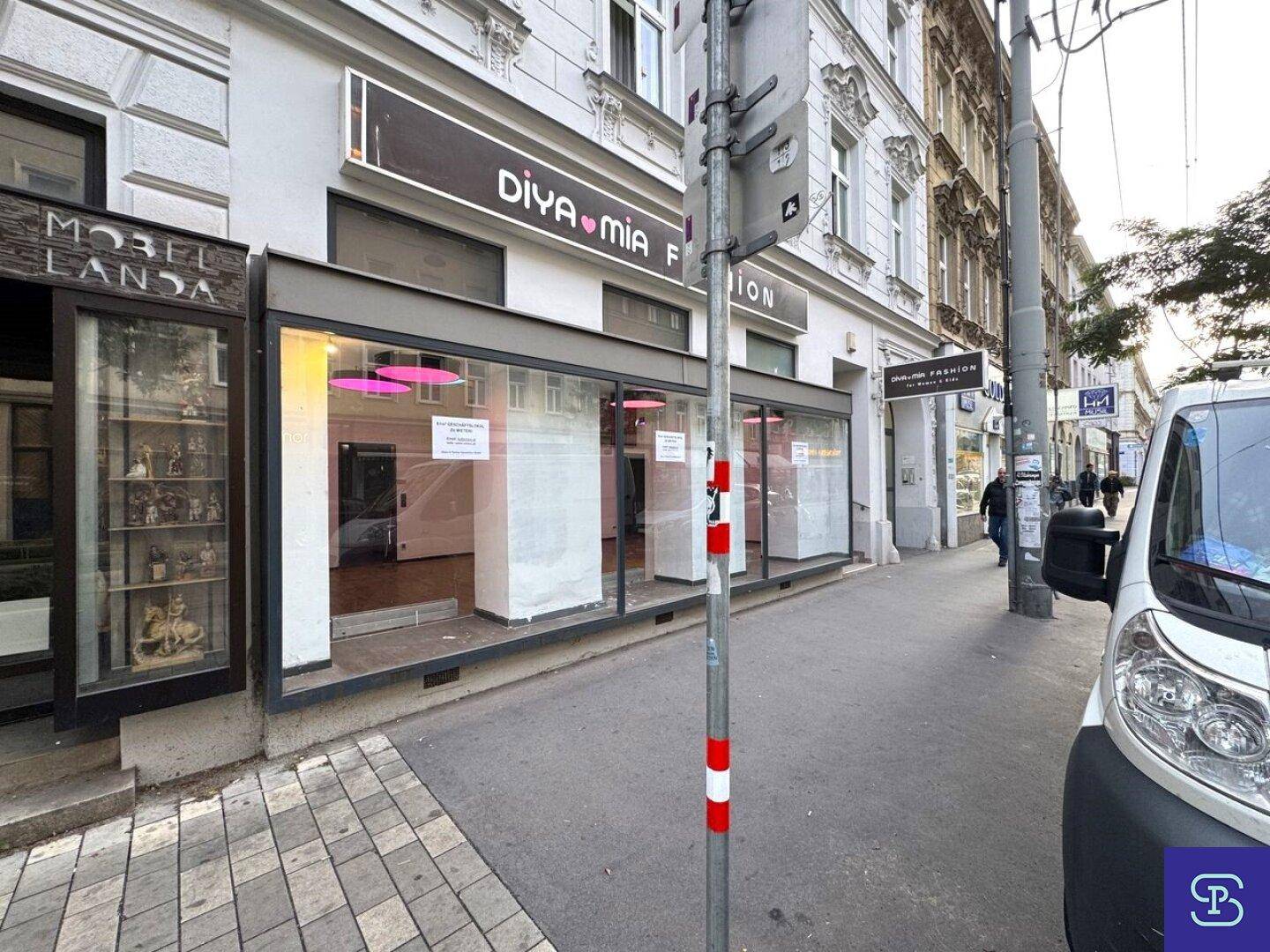Außenansicht des Geschäftsgebäudes mit großen Schaufenstern und einer belebten Straße davor.