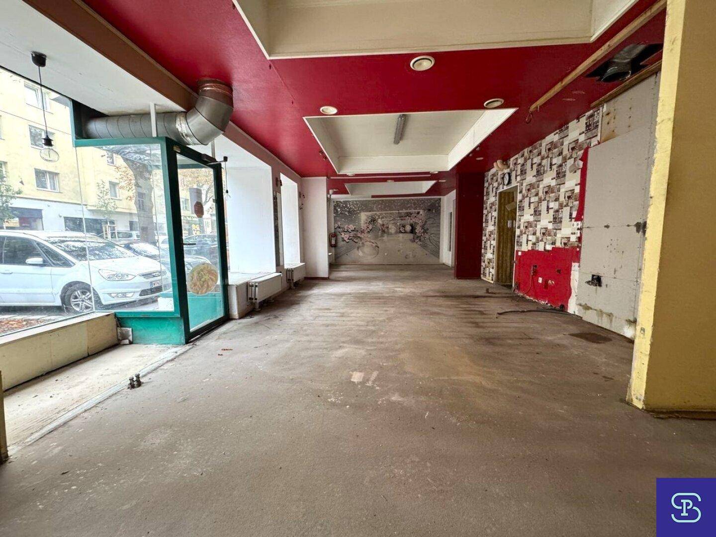 Weiterer Blick in den Ladenbereich mit roter Decke und teilweise entfernter Wandverkleidung.