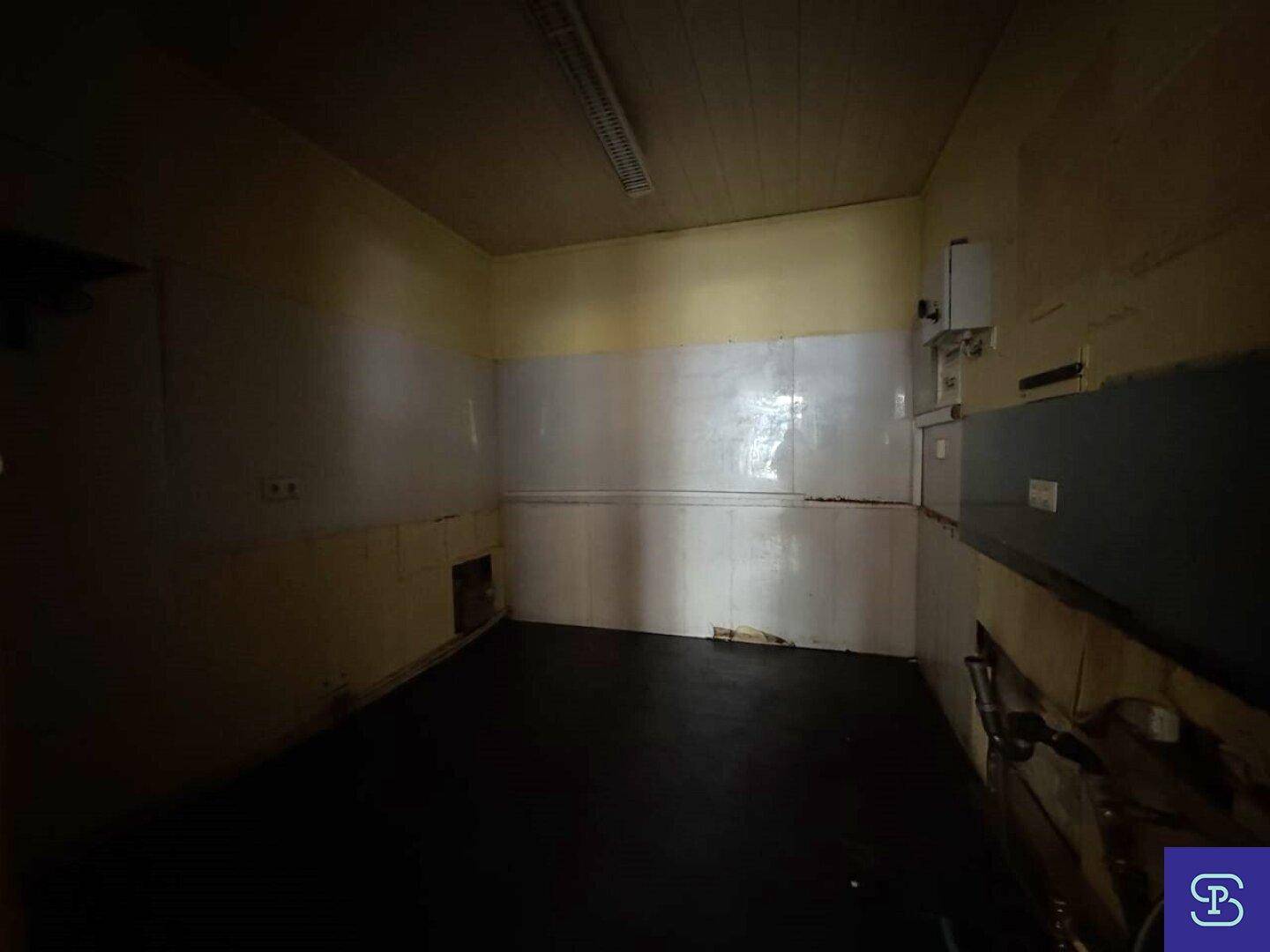 Dunkler Lagerraum mit gefliesten Wänden und einfacher Beleuchtung.