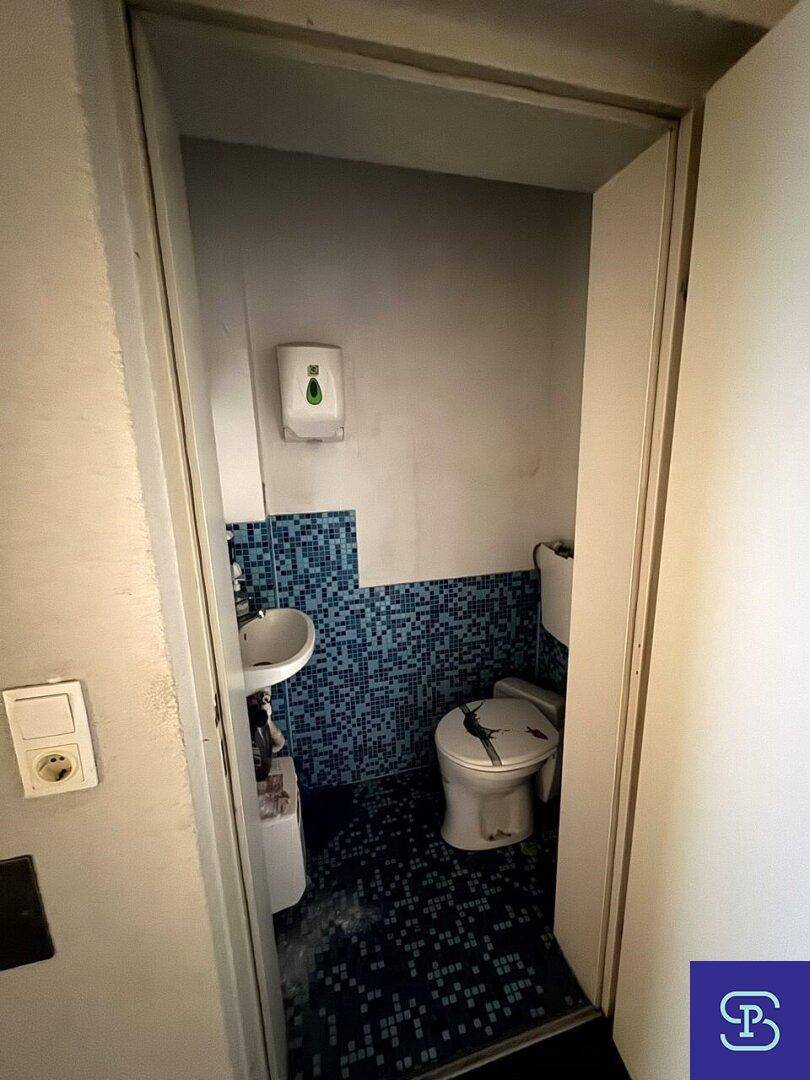 Kleine Toilette mit blauen Mosaikfliesen, Waschbecken und WC.