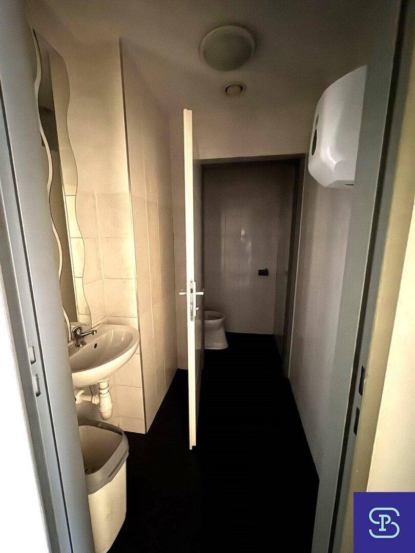 Langer Toilettenbereich mit Waschbecken und Zugang zu weiteren Kabinen.
