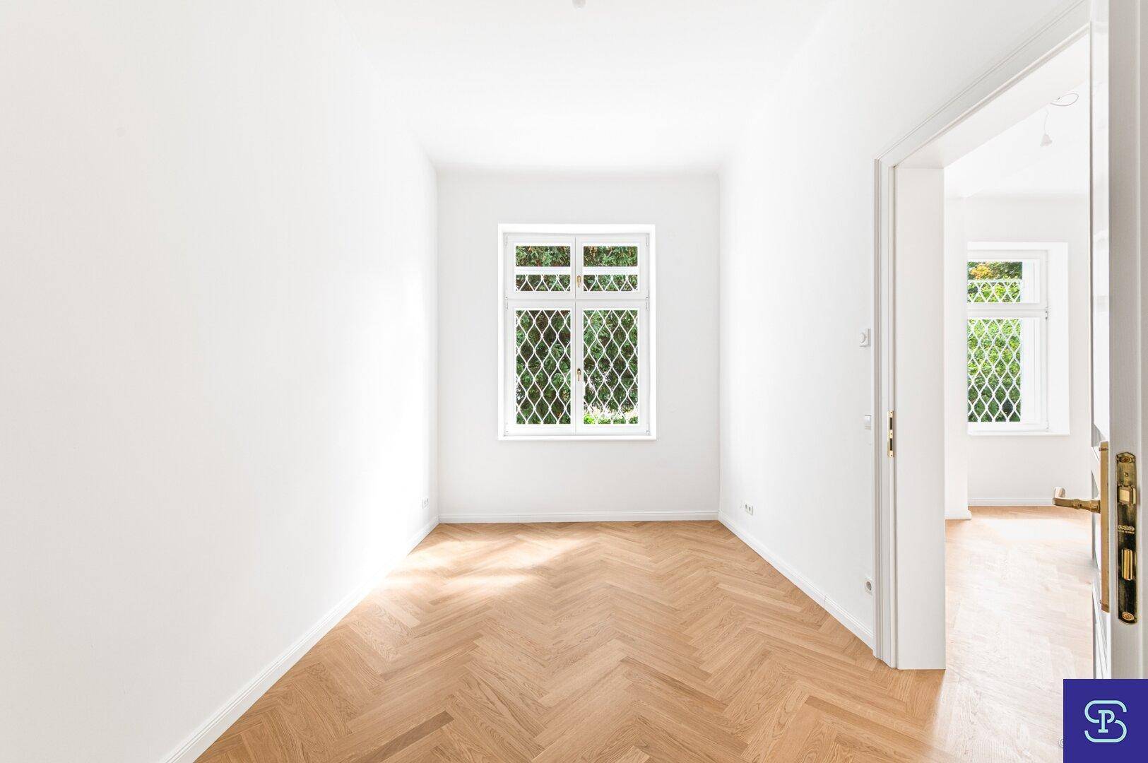 Gemütliches Zimmer mit Fischgrätparkett und Fenster zum Garten, ideal als Schlaf- oder Arbeitszimmer.