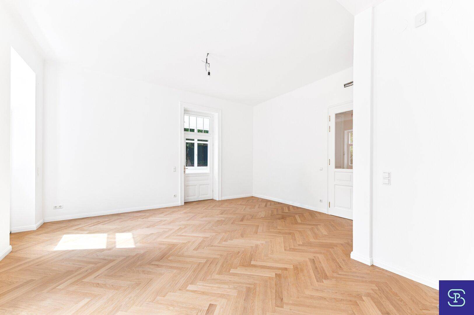 Helles Zimmer mit Fischgrätparkett und hohen Fenstern, ideal für ein großzügiges Wohnambiente.