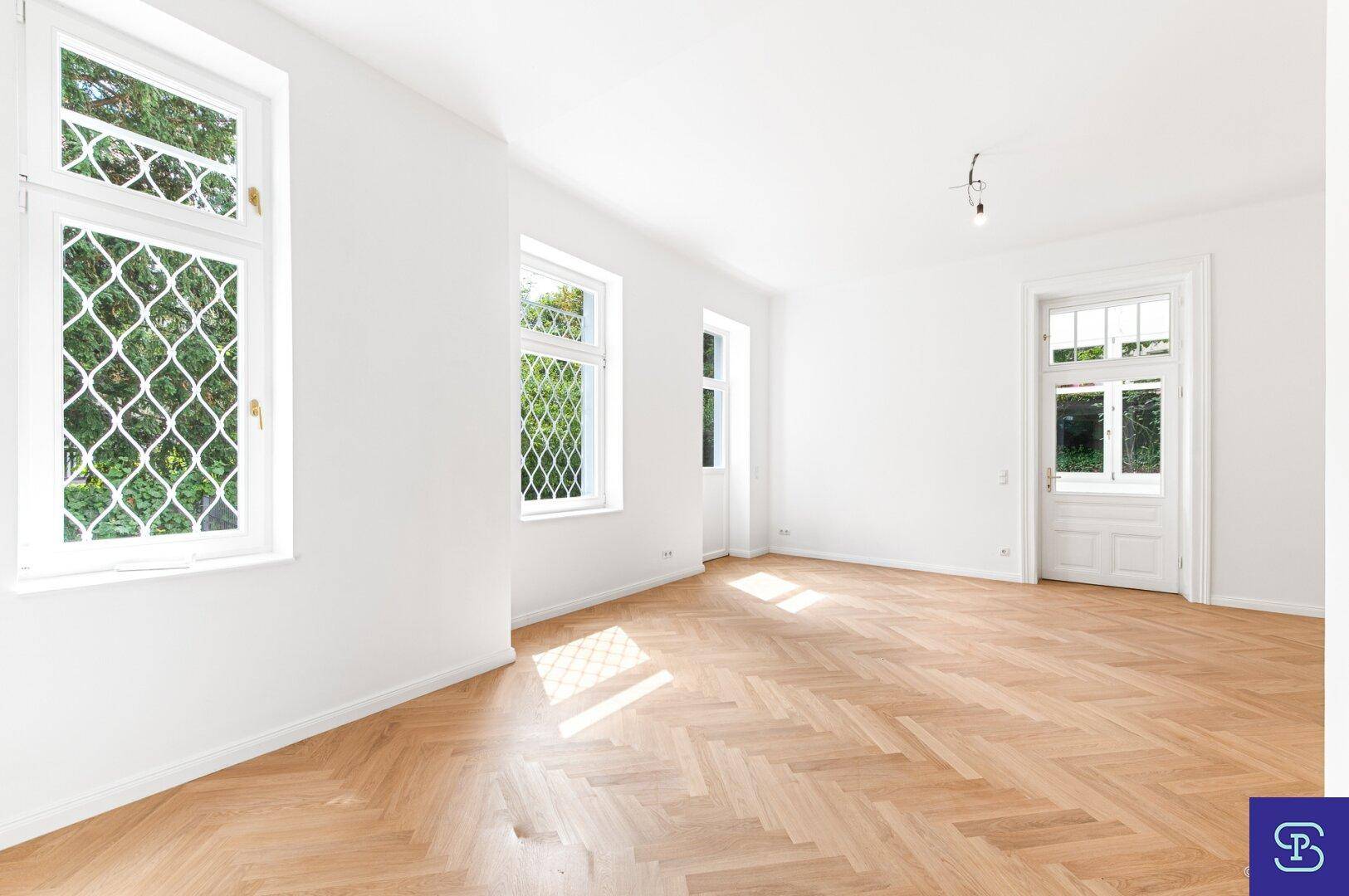 Lichtdurchflutetes Zimmer mit Fischgrätparkett und Blick ins Grüne, bietet viel Tageslicht.