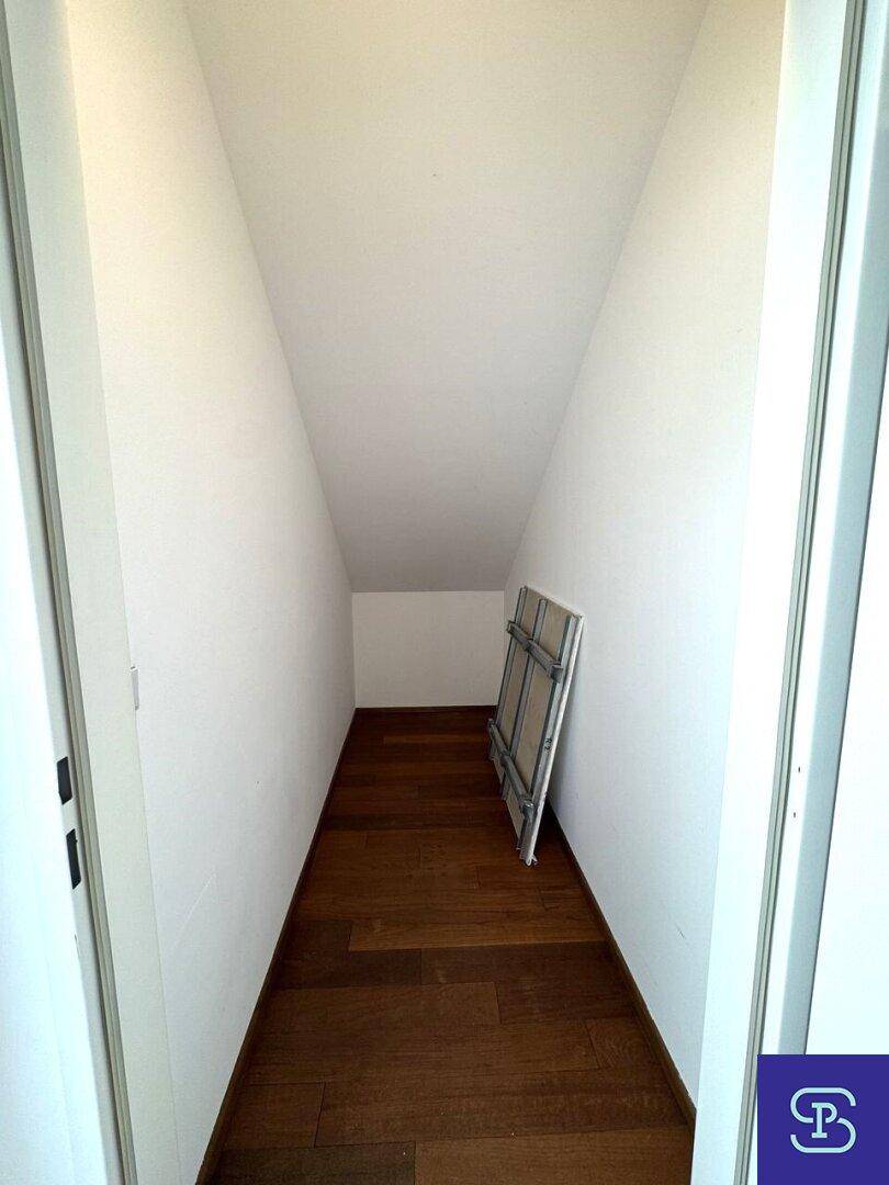 Kleiner Abstellraum mit Holzboden und schrägen Wänden unter dem Dach.
