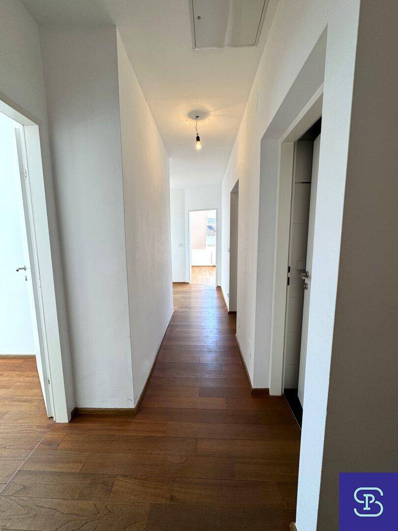 Langer, heller Flur mit Holzboden, der zu verschiedenen Räumen führt.