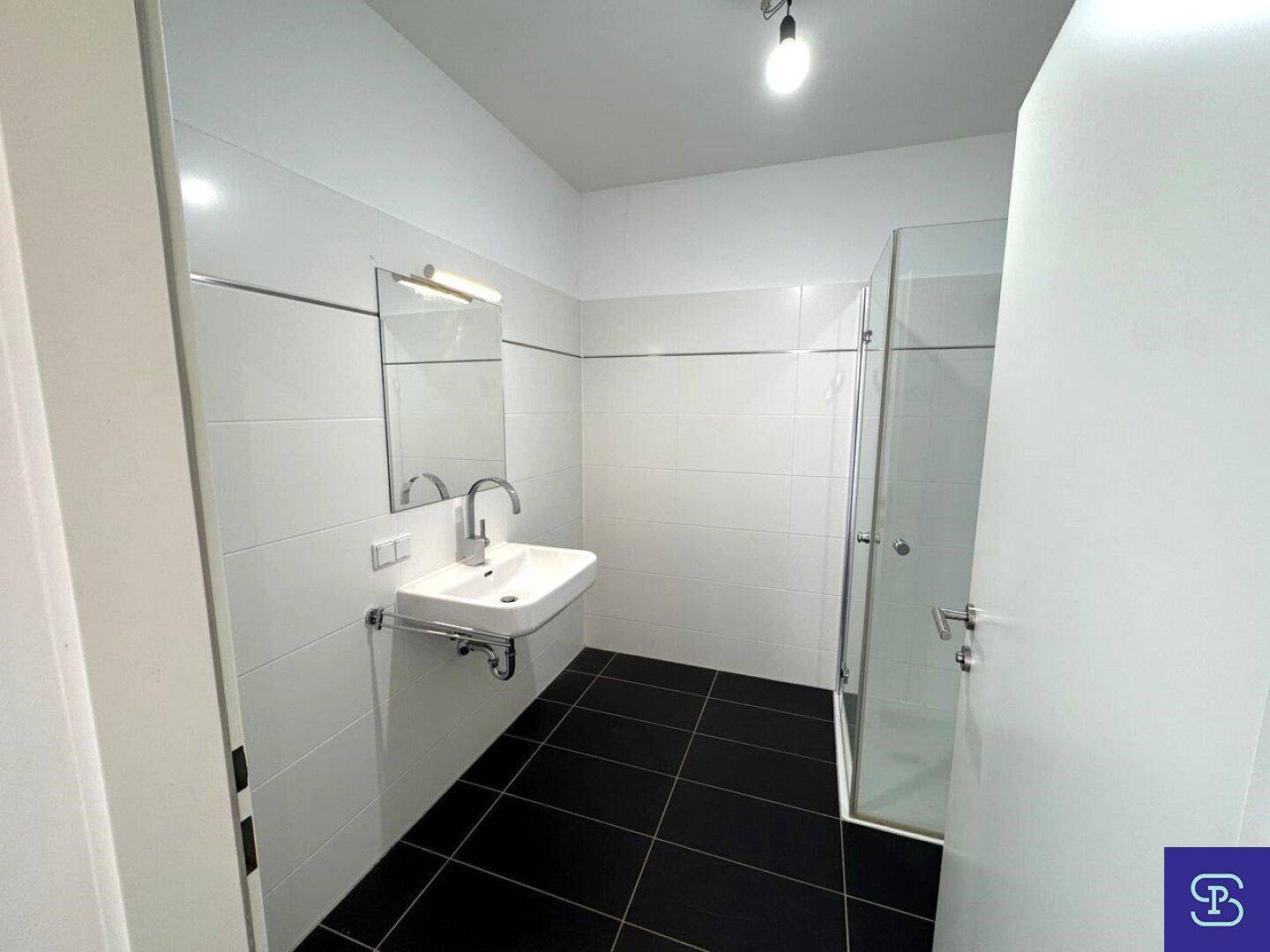 Modernes Badezimmer mit Einzelwaschbecken, Dusche und dunklen Bodenfliesen.