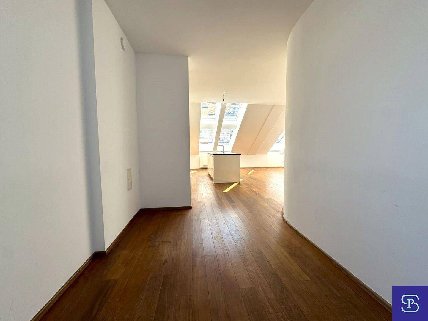 Heller Flur mit Holzboden, der zu einem offenen Wohnbereich mit Küche führt.