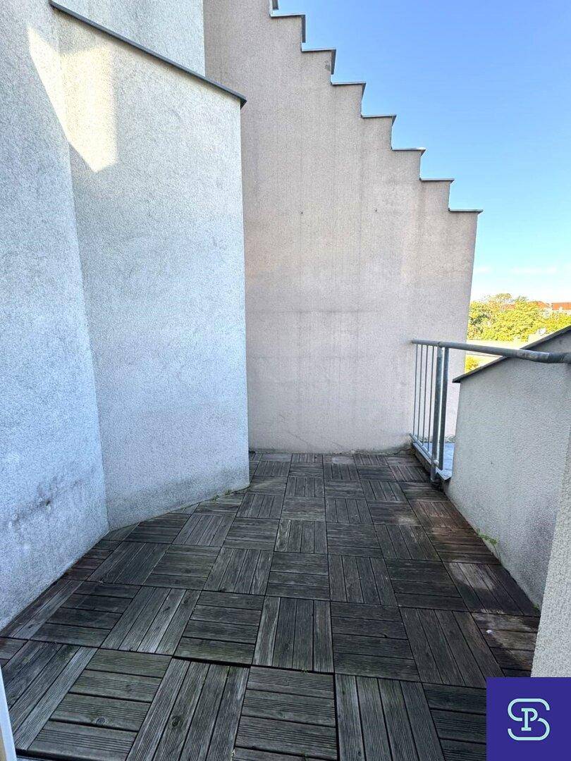 Kleiner Balkon mit Holzdielen und Blick auf die umliegenden Gebäude.