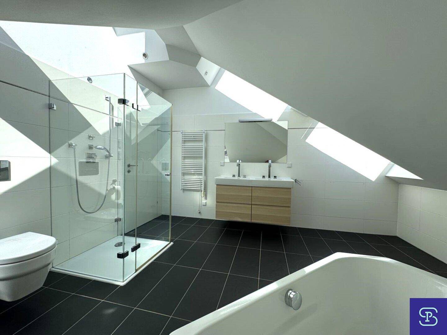 Elegantes Badezimmer mit Doppelwaschbecken, Dusche und Badewanne unter schrägen Dachfenstern.