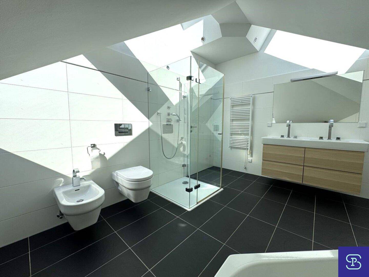 Helles Badezimmer mit Dusche, WC, Bidet und Doppelwaschbecken in modernem Design.