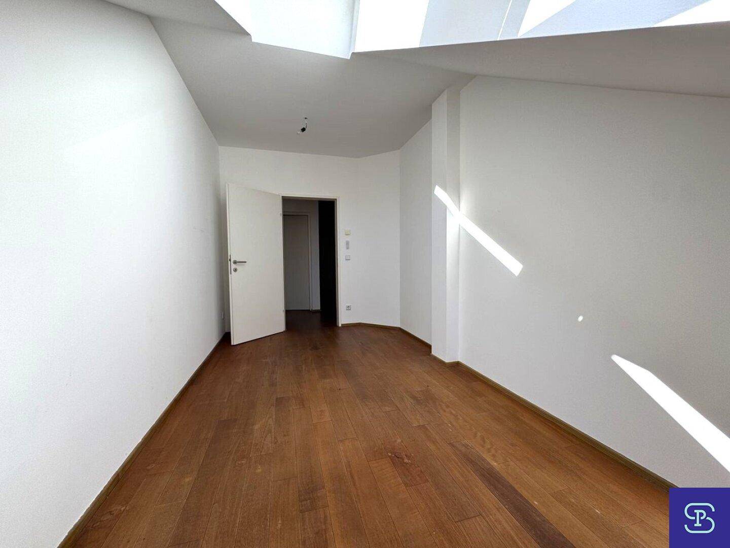 Leerer Raum mit Holzboden und weiß gestrichenen Wänden, bereit zur individuellen Gestaltung.