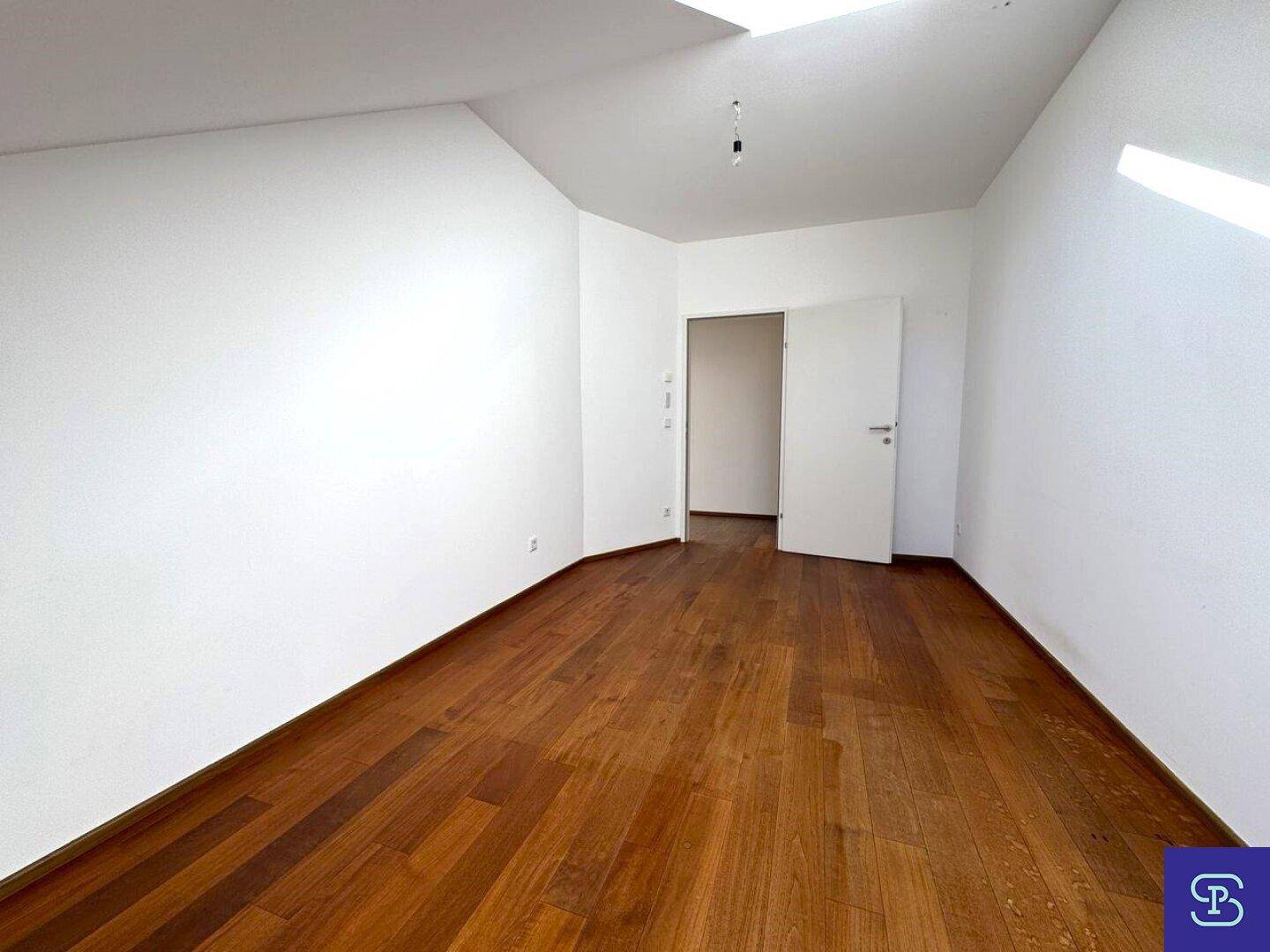 Leerer Raum mit Holzboden und weiß gestrichenen Wänden, bereit zur individuellen Gestaltung.