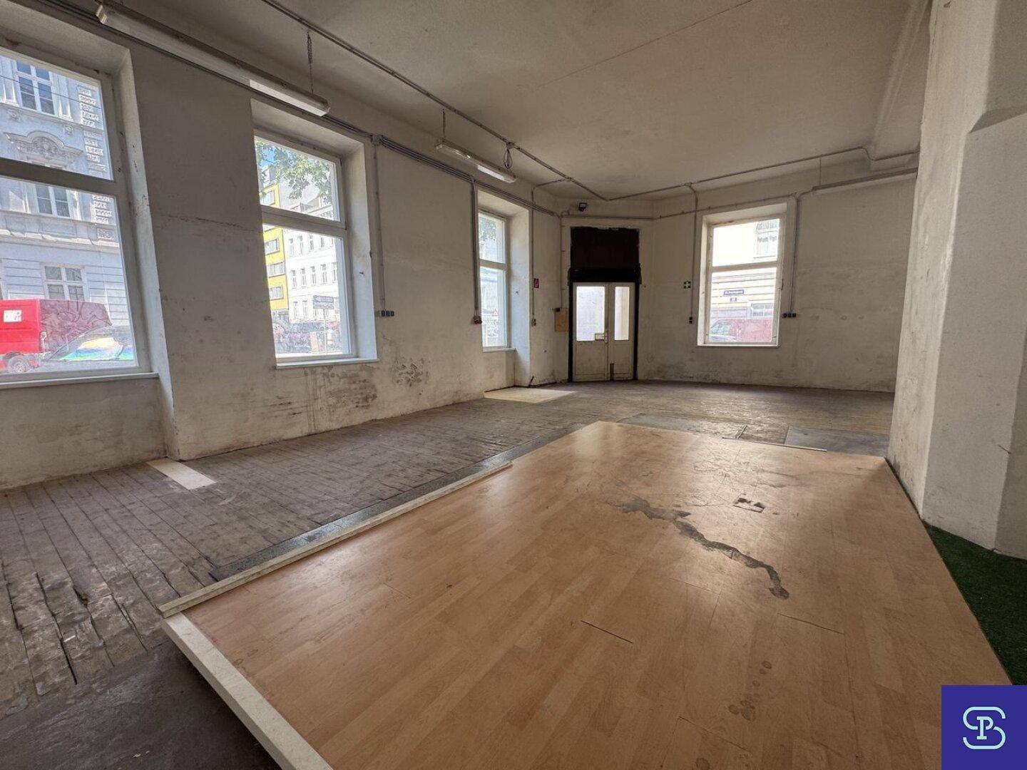 Großer Gewerberaum mit einer Mischung aus abgenutztem Holzboden und einer neuen Holzplattform.