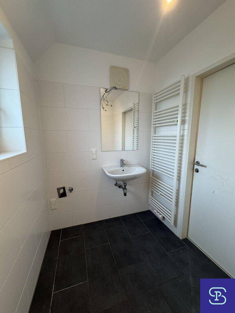 Badezimmer mit Waschbecken, Spiegel, beheiztem Handtuchhalter und dunklem Fliesenboden.