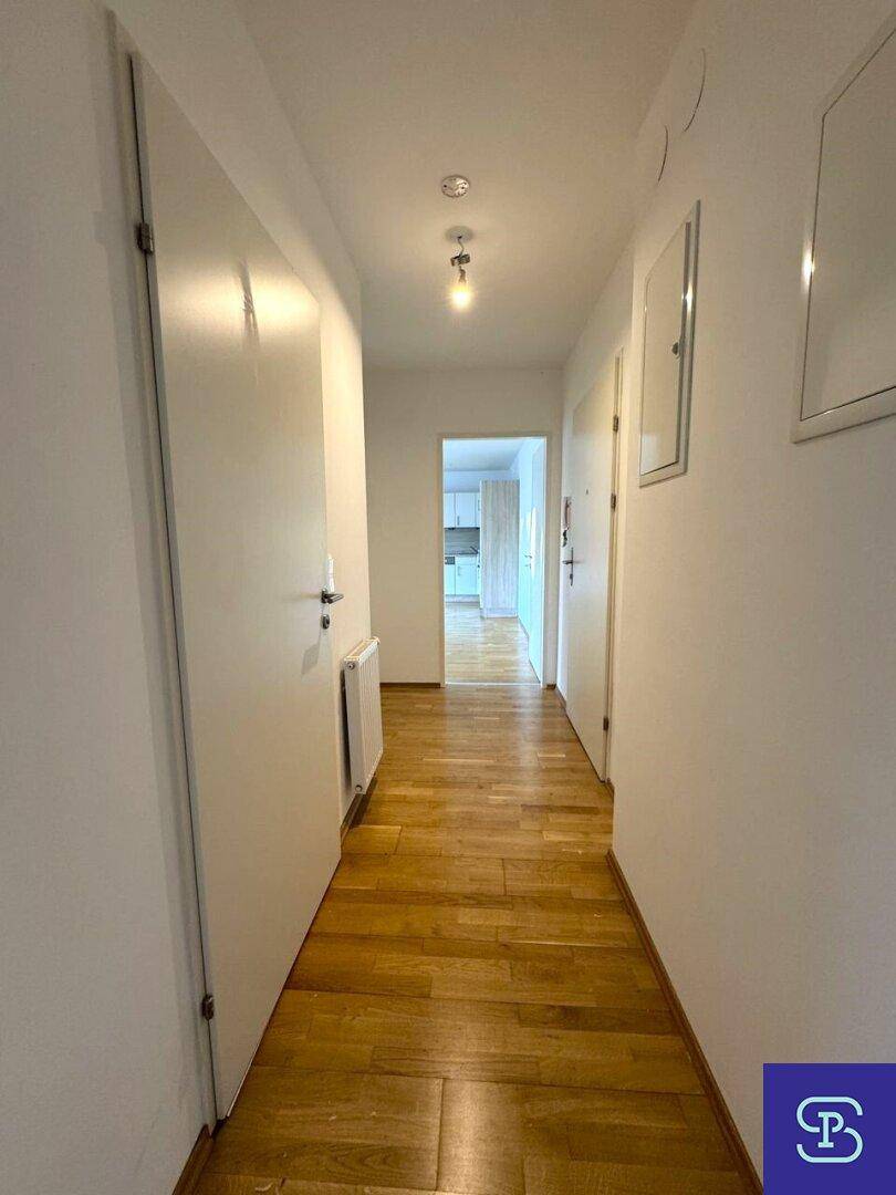 Heller Flur mit Holzboden und mehreren weißen Türen, die zu den Zimmern führen.