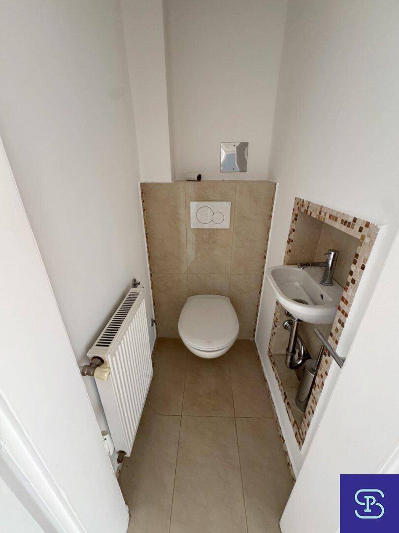 Kleines Gäste-WC mit wandhängender Toilette, Handwaschbecken und Heizkörper.