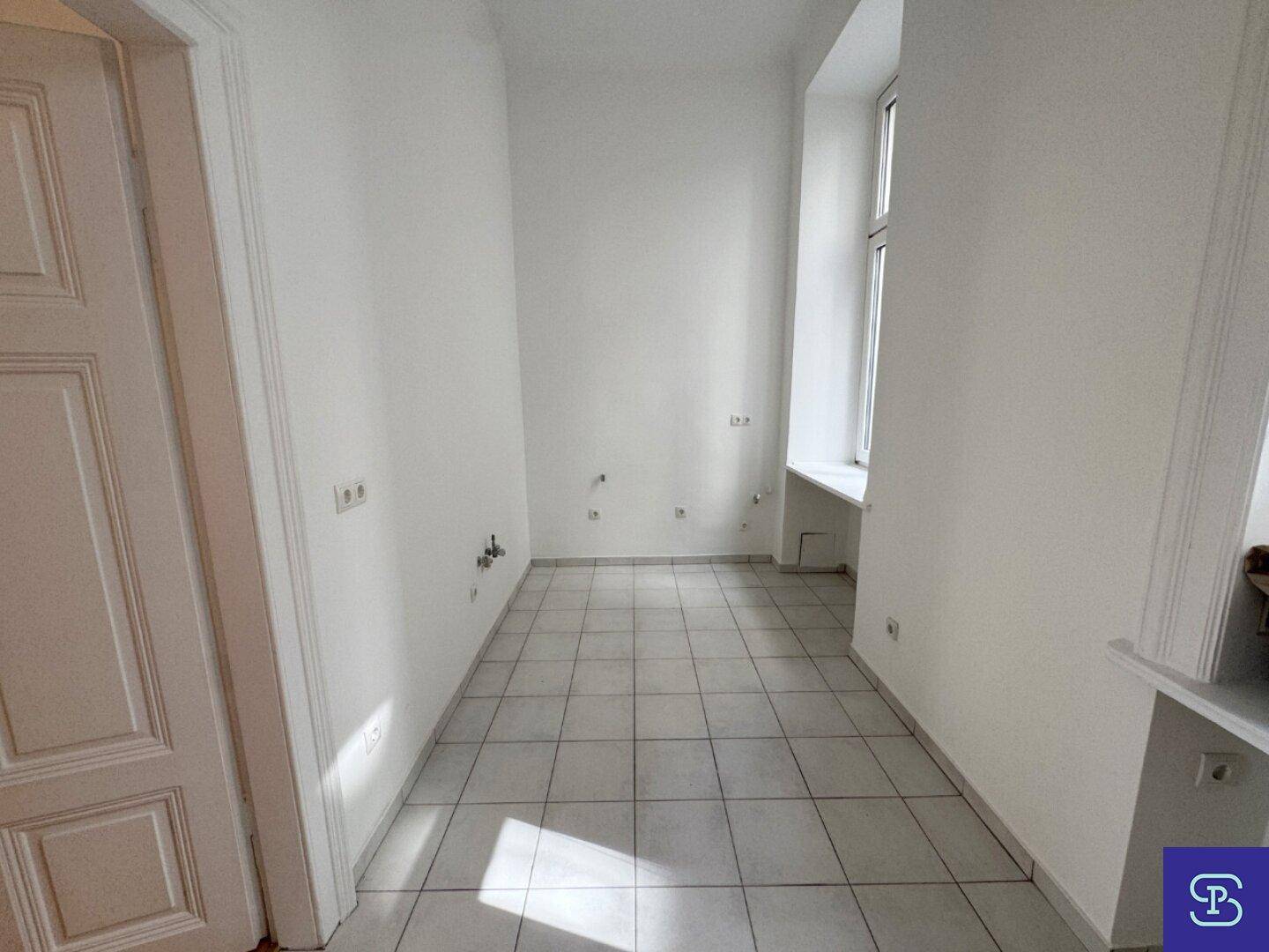 Heller Raum mit Fliesenboden und Fenster, ideal für die Einrichtung einer modernen Küche.