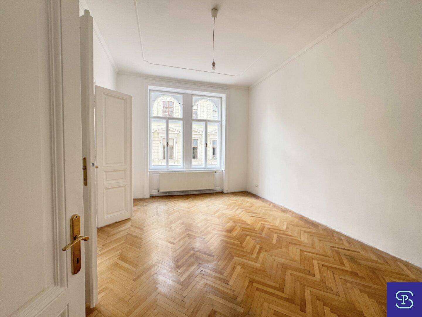 Geräumiges Zimmer mit Fischgrätparkett und hohen Fenstern, das viel natürliches Licht erhält.