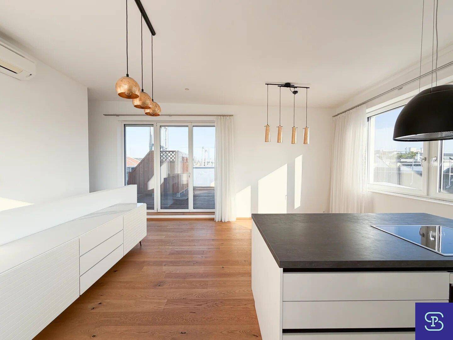 Geräumiger Wohnbereich mit Holzboden, weißem Sideboard und großen Fenstern zur Terrasse.