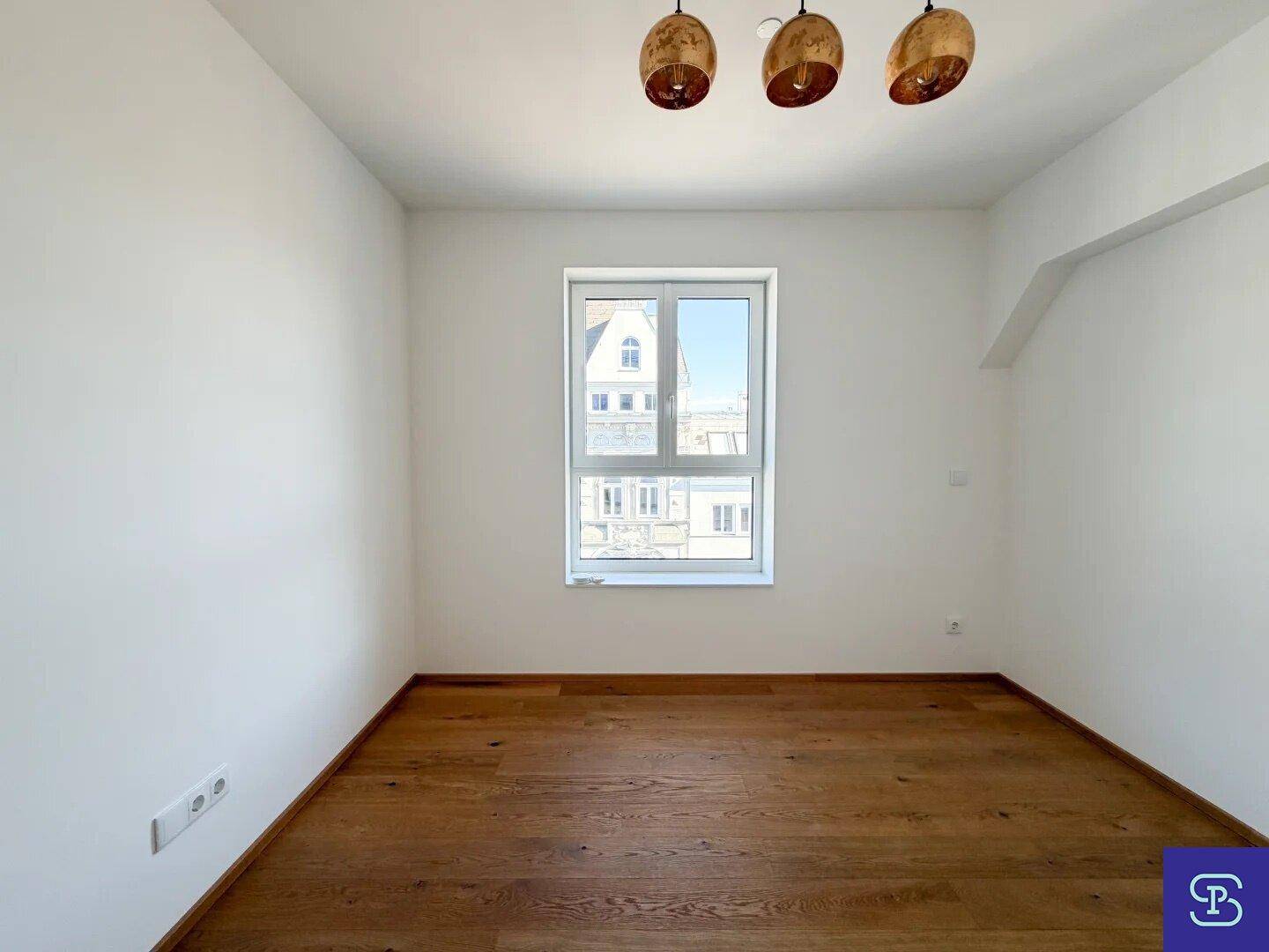 Leeres Zimmer mit Holzboden und weiß gestrichenen Wänden, ideal als Schlafzimmer.