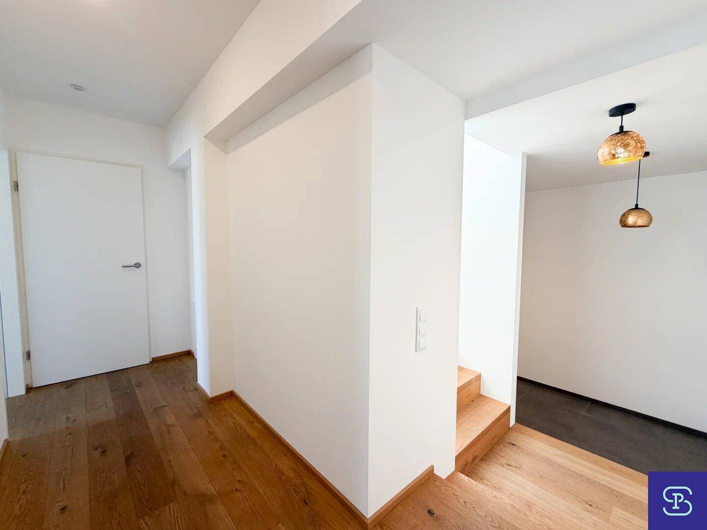 Heller Flur mit Holztreppe, kombiniertem Fliesen- und Holzboden.