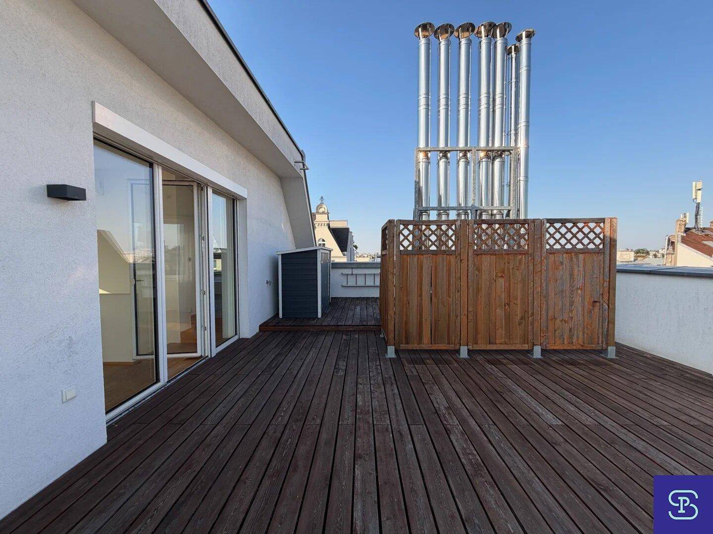 Geräumige Dachterrasse mit Holzbelag, Sichtschutz und Zugang zum Innenbereich.