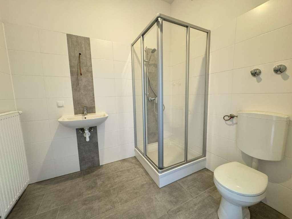 Badezimmer mit Duschkabine, WC und Heizkörper.