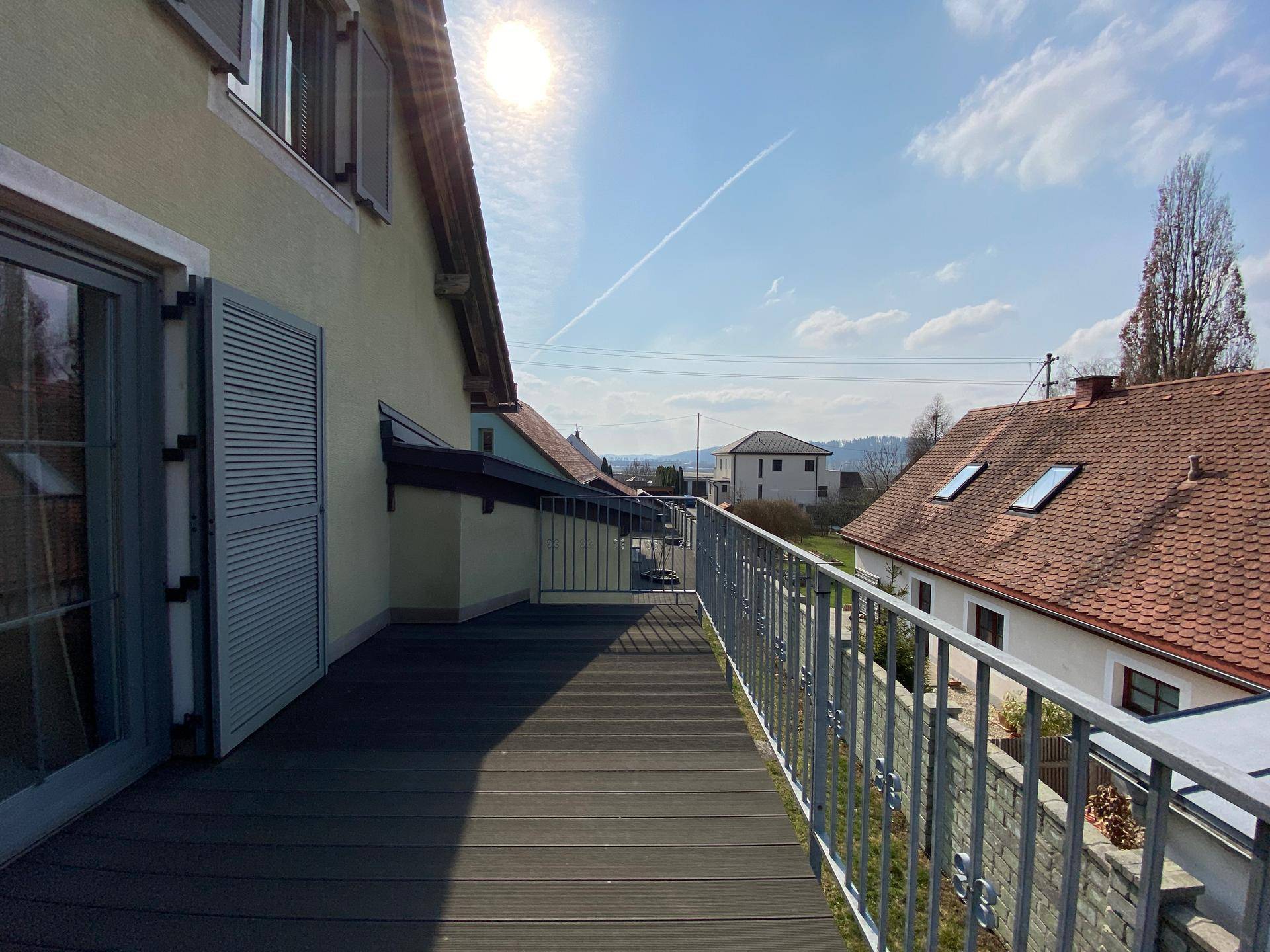 Langer Balkon mit Holzboden und Metallgeländer, bietet einen weiten Blick.