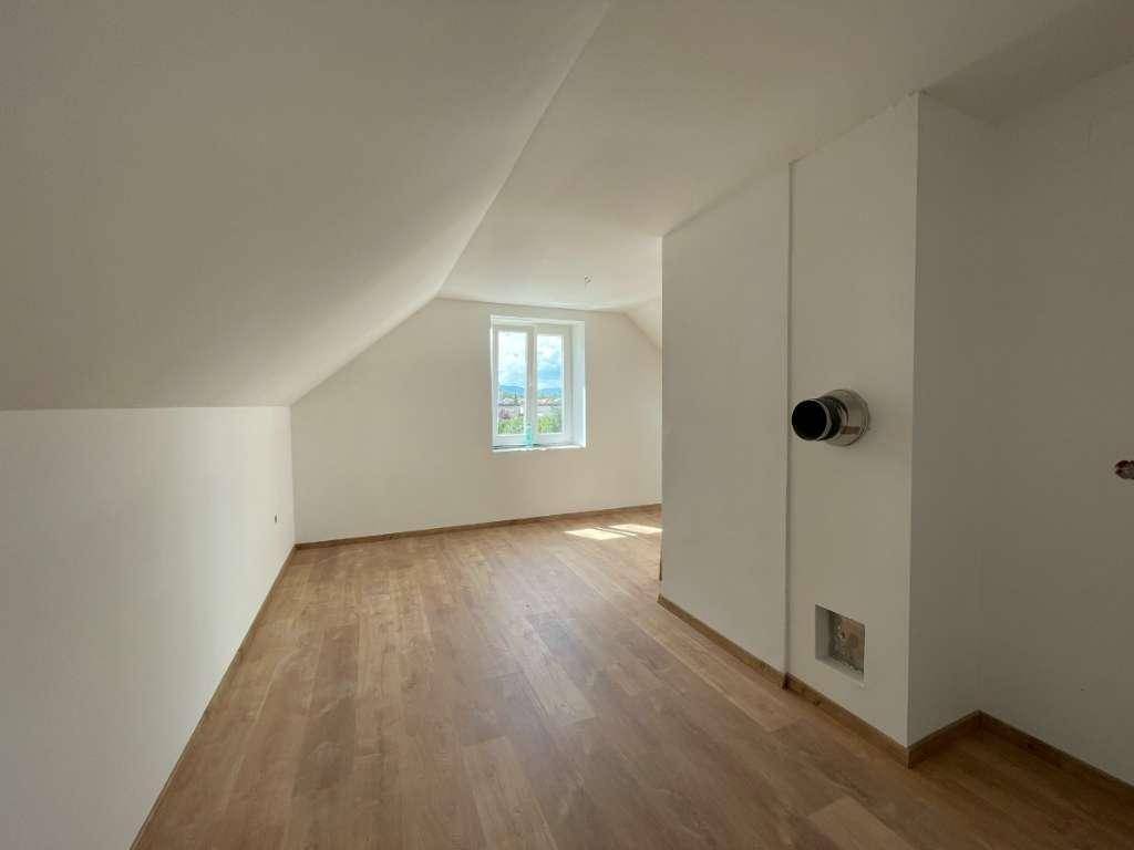 Heller Raum im Dachgeschoss mit Laminatboden und schrägen Wänden.