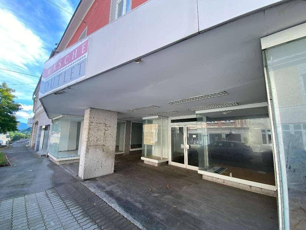 Eingangsbereich des Geschäfts mit großer Glasfront und überdachtem Gehweg, der zum Laden führt.