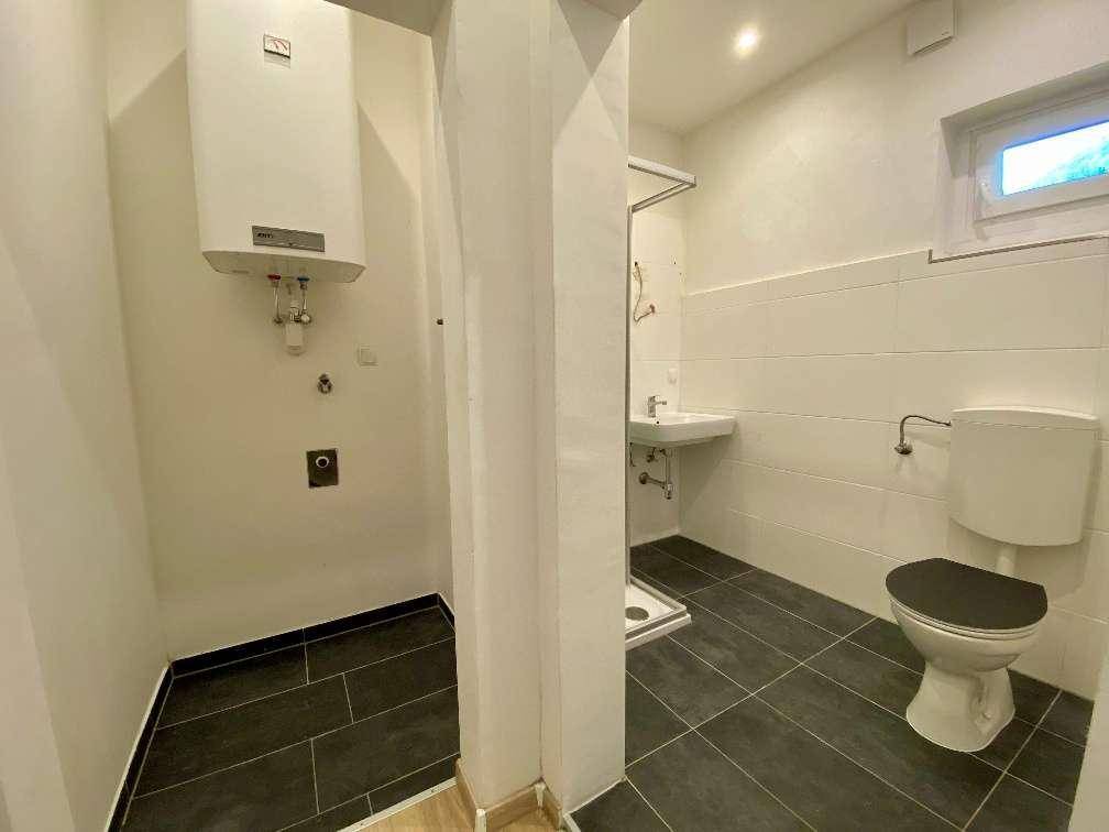 Modernes Badezimmer mit Dusche, WC, Waschbecken und Fenster für Tageslicht.