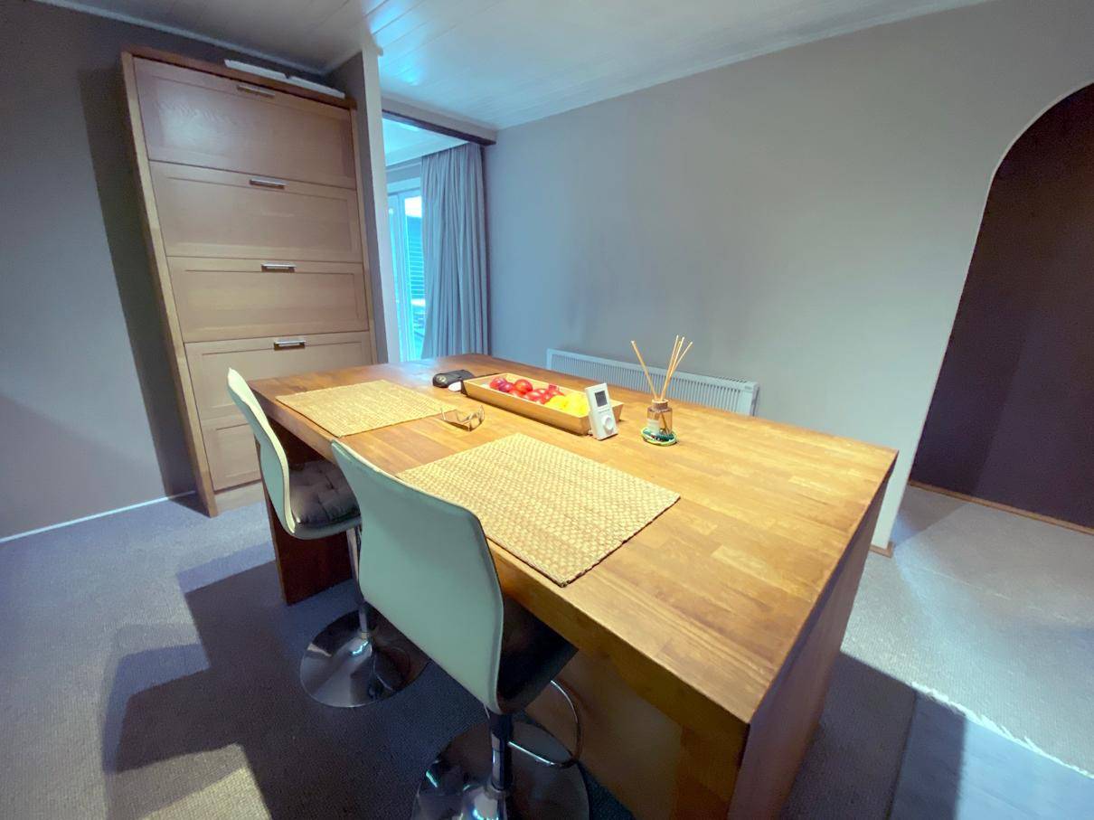 Heller Essbereich mit Holztisch und Barhockern, ideal für Frühstück oder schnelle Mahlzeiten.