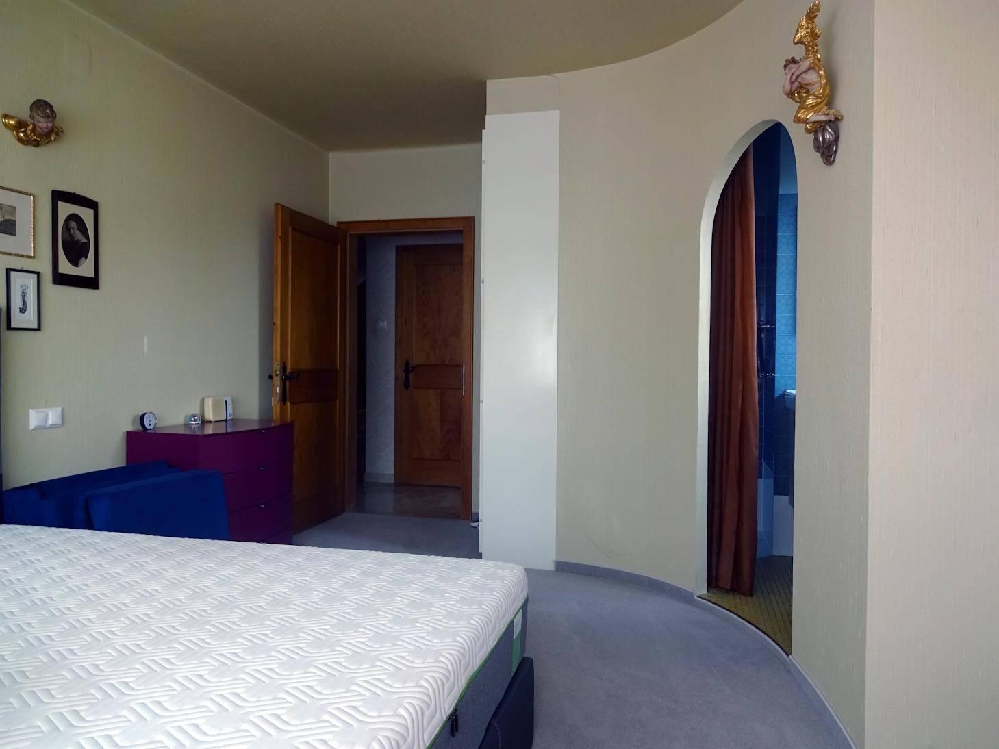 Schlafzimmer mit hellem Teppichboden und direktem Zugang zum Badezimmer.