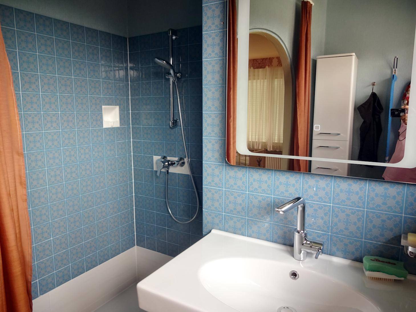 Badezimmer mit blauen Fliesen, Dusche und Waschbecken.