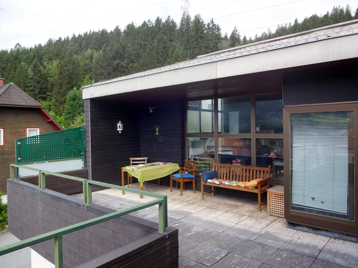 Große überdachte Terrasse mit Sitzgelegenheiten und Blick auf die Umgebung.