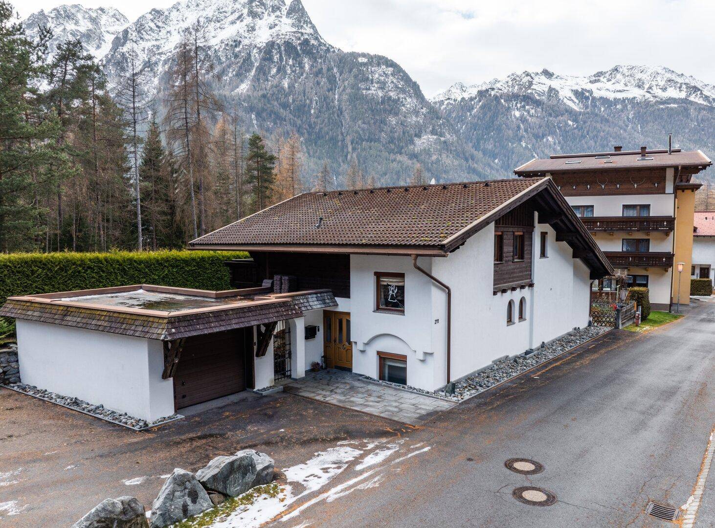 Charmantes Einfamilienhaus mit Garage und beeindruckendem Bergpanorama im Hintergrund.