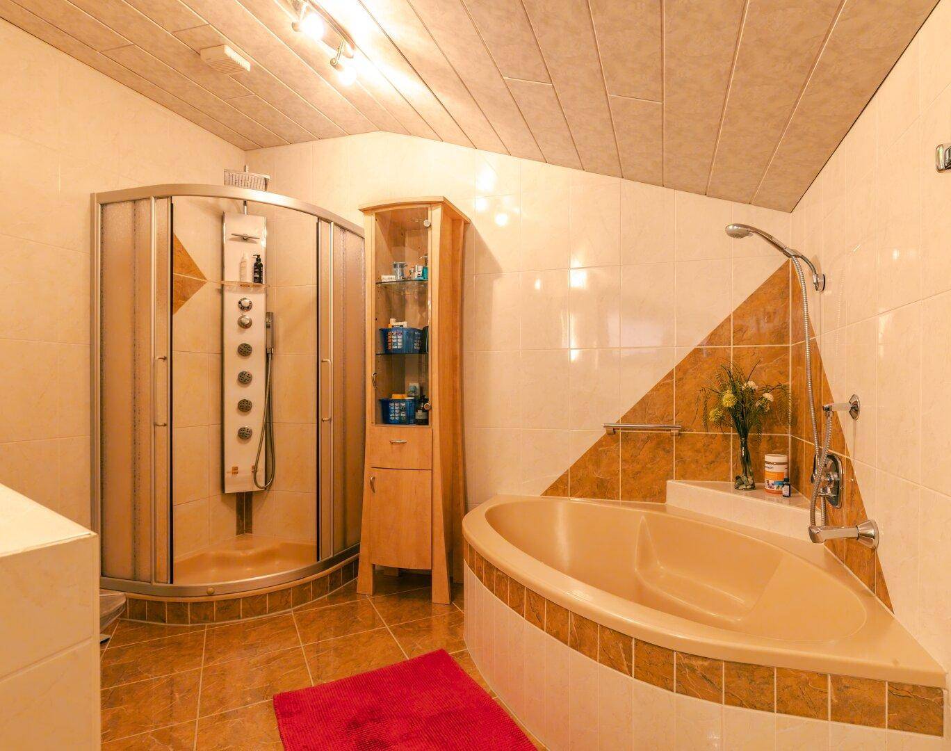 Geräumiges Badezimmer mit Eckbadewanne, Duschkabine und schrägen Decken.