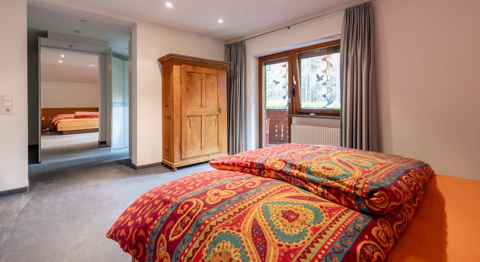 Schlafzimmer mit Doppelbett, Holzschrank und Zugang zu einem Balkon.