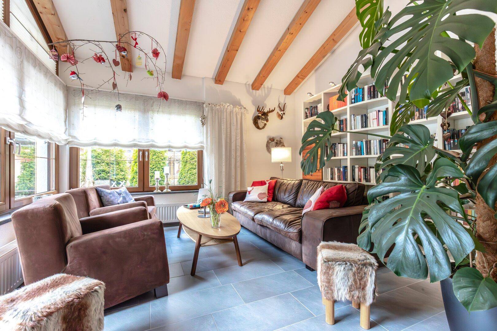 Wohnzimmer mit Ledersofa, Bücherregal, Holzbalken und traditioneller Dekoration.