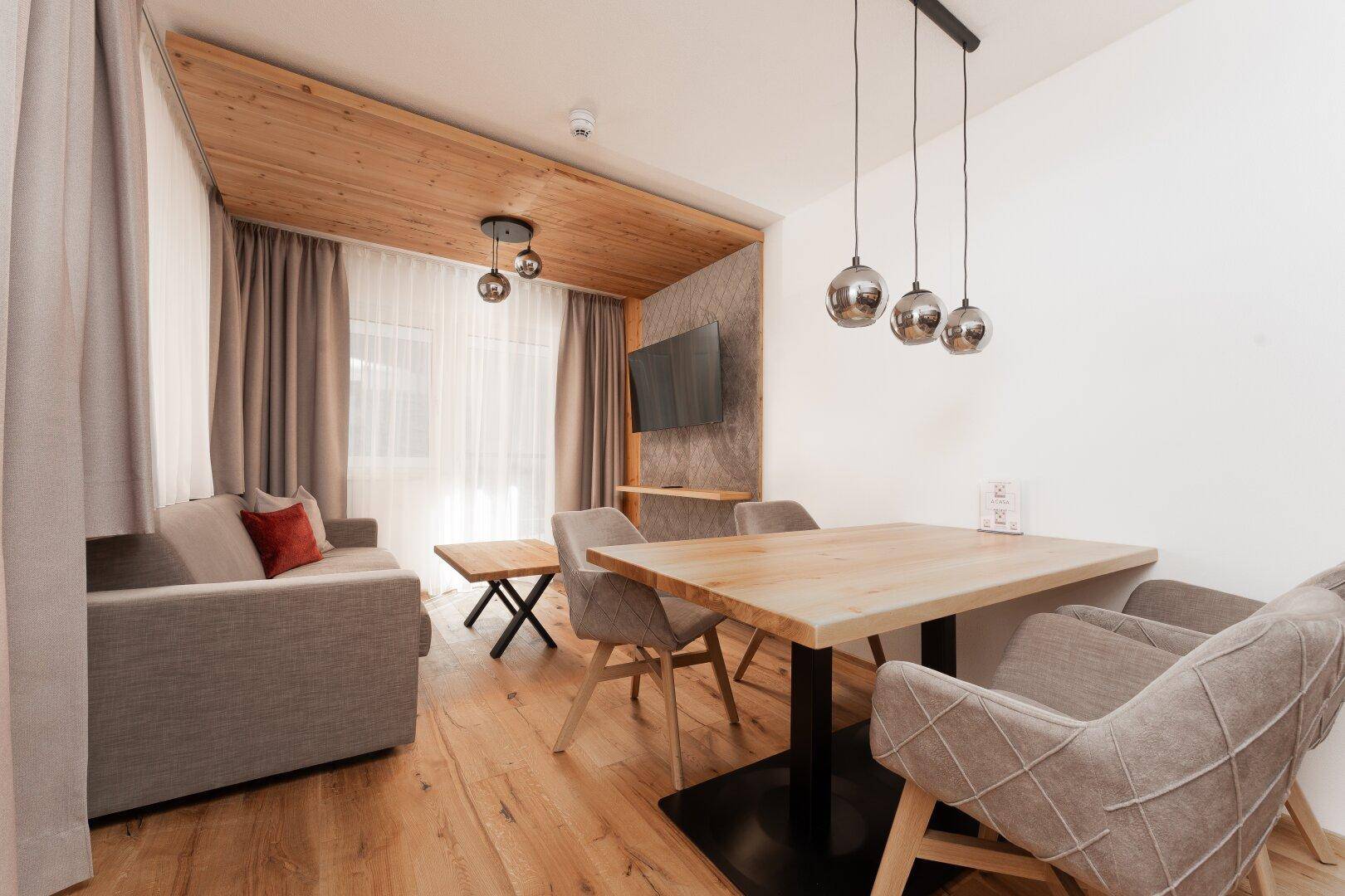 Gemütlicher Wohn-Essbereich mit Holzboden, modernem Esstisch und bequemer Couch, ideal für gesellige Abende.