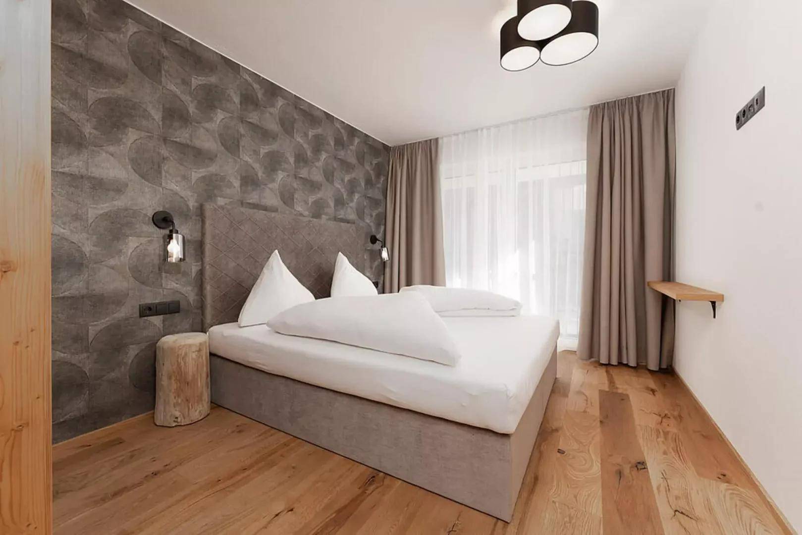 Modernes Schlafzimmer mit stilvoller Tapete, Holzboden und großen Fenstern für viel Tageslicht.